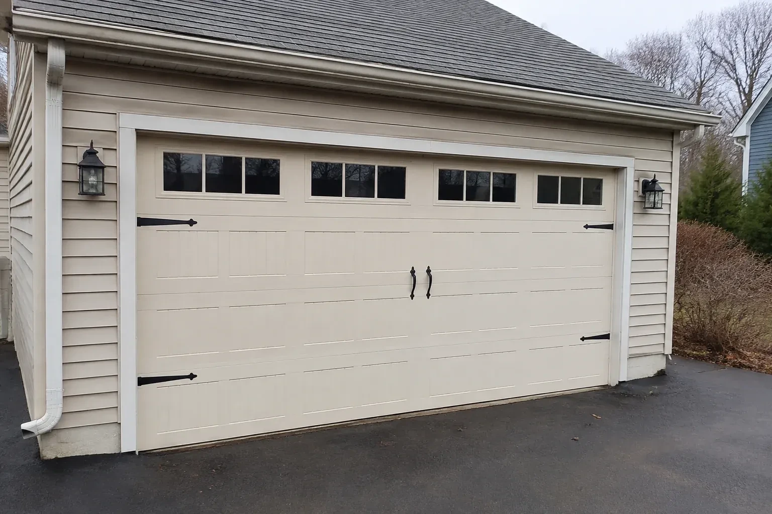 Cream carriage-house-style garage door with dark decorative hardware. — Carriage-House Garage Door Installation, Wasaga Beach